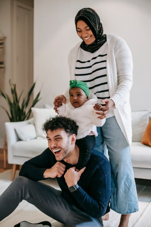 Cheerful diverse family with toddler daughter having fun at home